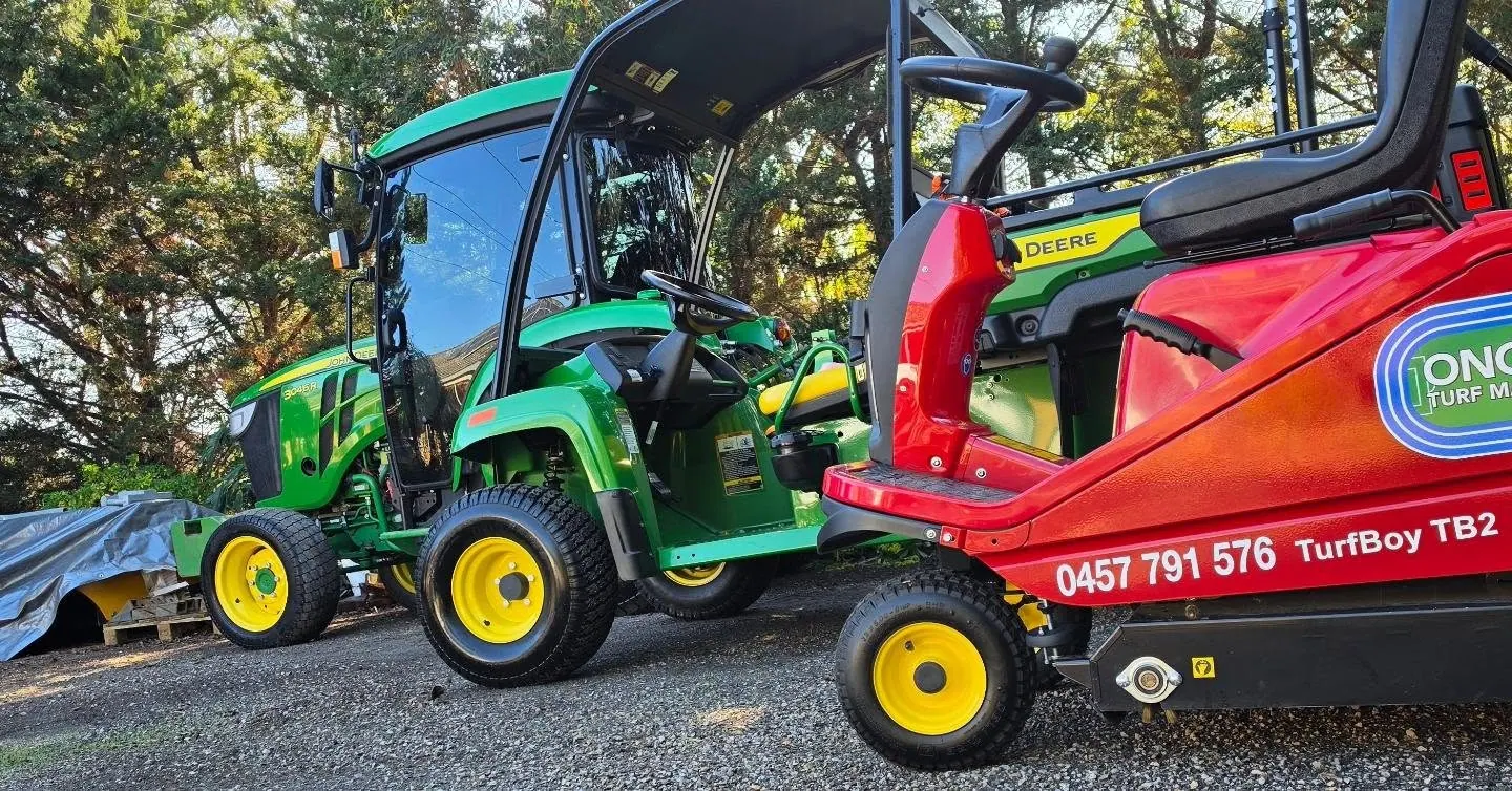 Close view of the Ongrade branded turf sweeper beside a compact tractor